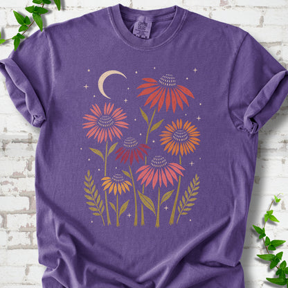 Grape T-shirt laid flat, showing warm-toned coneflowers with green leaves, a cream crescent moon and small stars.