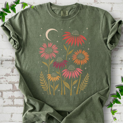 Moss T-shirt laid flat, showing warm-toned coneflowers with green leaves, a cream crescent moon and small stars.