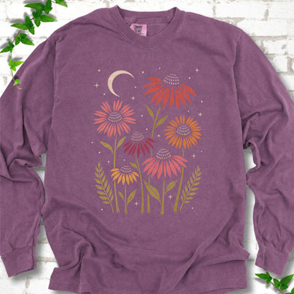 Berry long sleeve tee laid flat, showing warm-toned coneflowers with green leaves, a cream crescent moon and small stars.