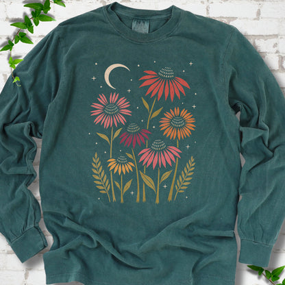 Blue Spruce long sleeve tee laid flat, showing warm-toned coneflowers with green leaves, a cream crescent moon and small stars.