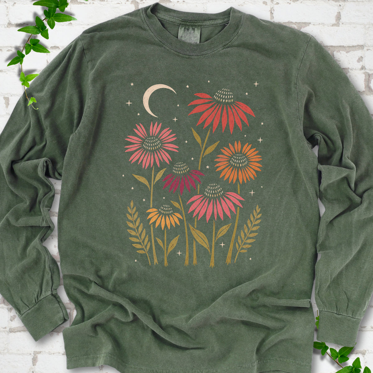 Hemp long sleeve tee laid flat, showing warm-toned coneflowers with green leaves, a cream crescent moon and small stars.