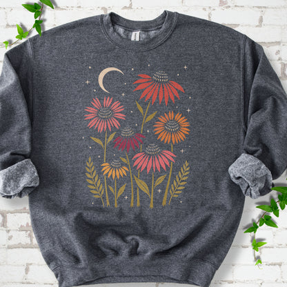 Dark Heather classic sweatshirt laid flat, showing warm-toned coneflowers with green leaves, a cream crescent moon and small stars.