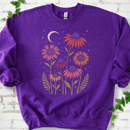 Purple classic sweatshirt laid flat, showing warm-toned coneflowers with green leaves, a cream crescent moon and small stars.