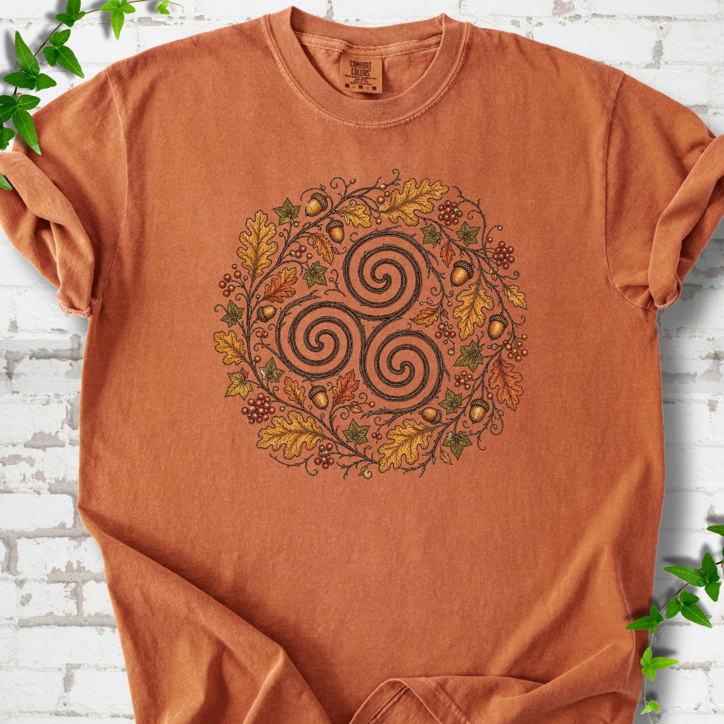 Yam Comfort Colors® T-shirt flat lay with a Celtic-inspired triskele and autumn oak wreath design.