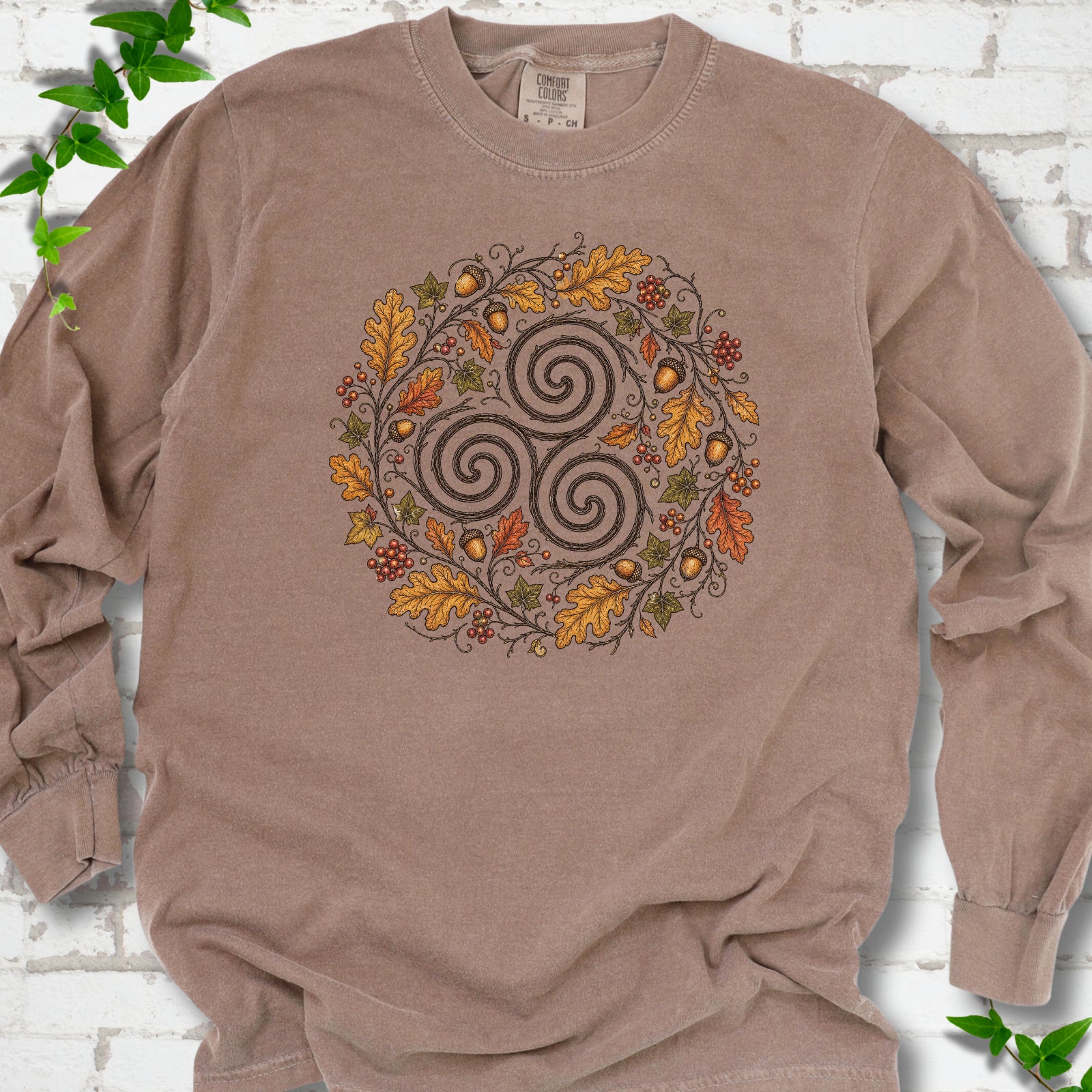 Espresso Comfort Colors® long sleeve T-shirt flat lay with a Celtic-inspired triskele and autumn oak wreath design.