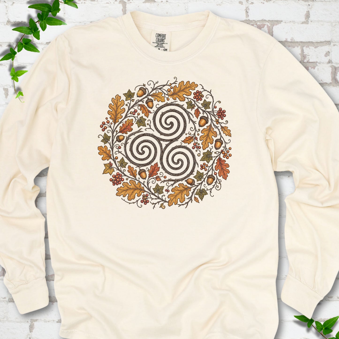 Ivory Comfort Colors® long sleeve T-shirt flat lay with a Celtic-inspired triskele and autumn oak wreath design.