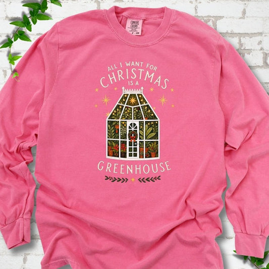 Crunchberry long sleeve T-shirt laid flat, featuring a plant-filled glass greenhouse with a red bow, gold stars and the slogan 'All I want for Christmas is a greenhouse'.