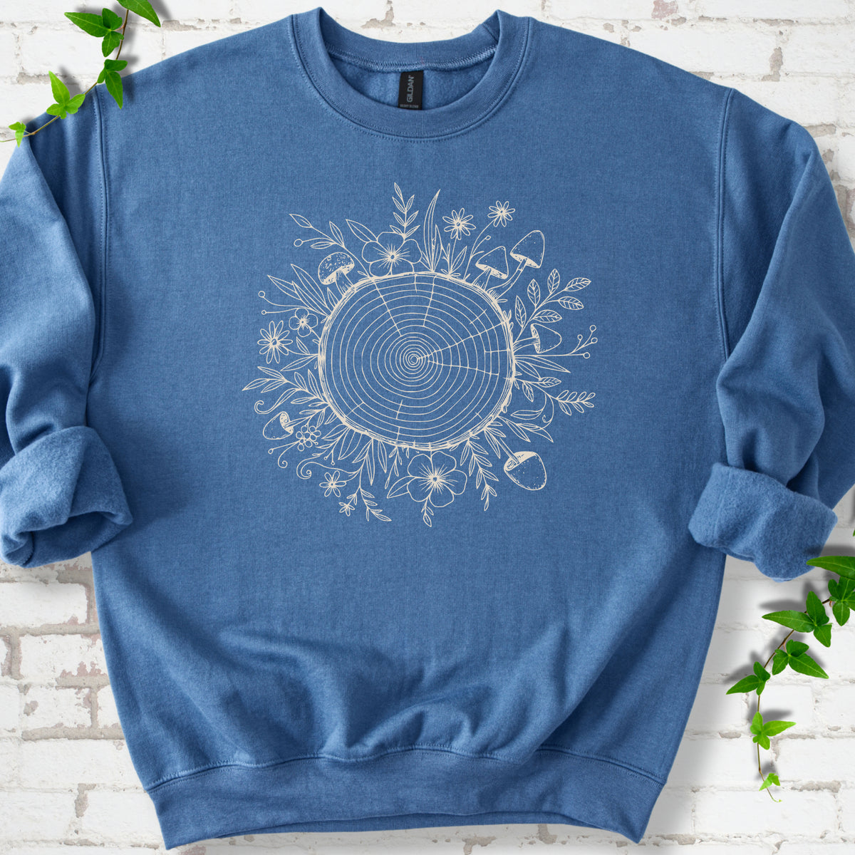 Indigo Blue classic sweatshirt shown flat with the Circles of Life tree-ring, wildflower and mushroom graphic