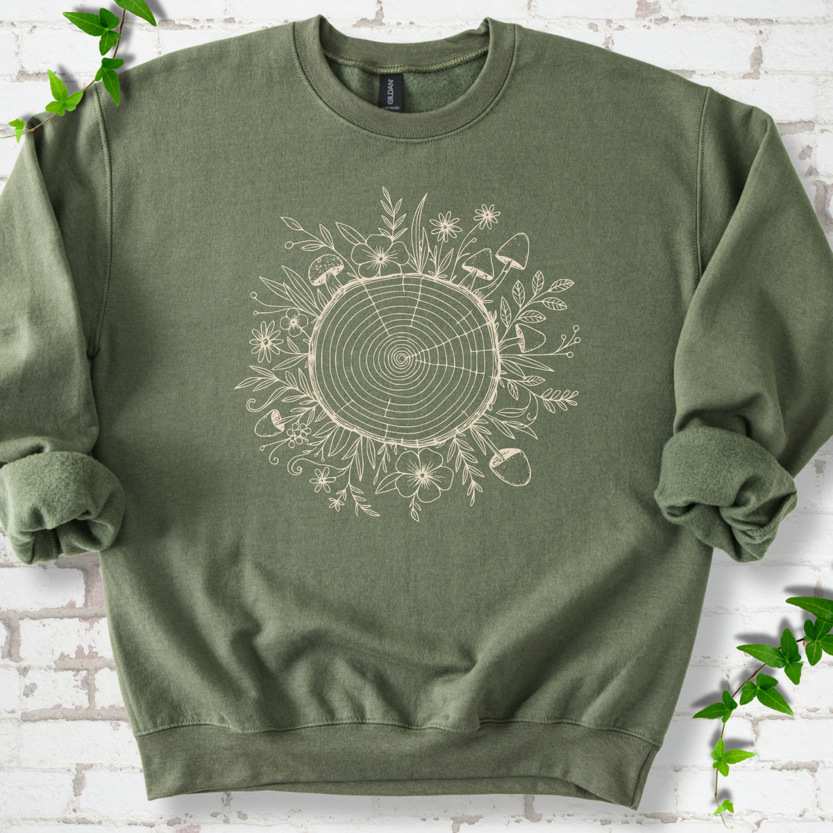 Military Green classic sweatshirt shown flat with the Circles of Life tree-ring, wildflower and mushroom graphic