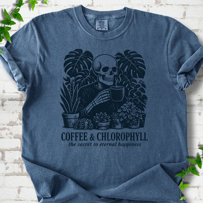 Denim Comfort Colors® short sleeve T-shirt flat lay featuring a distressed skeleton drinking coffee among houseplants