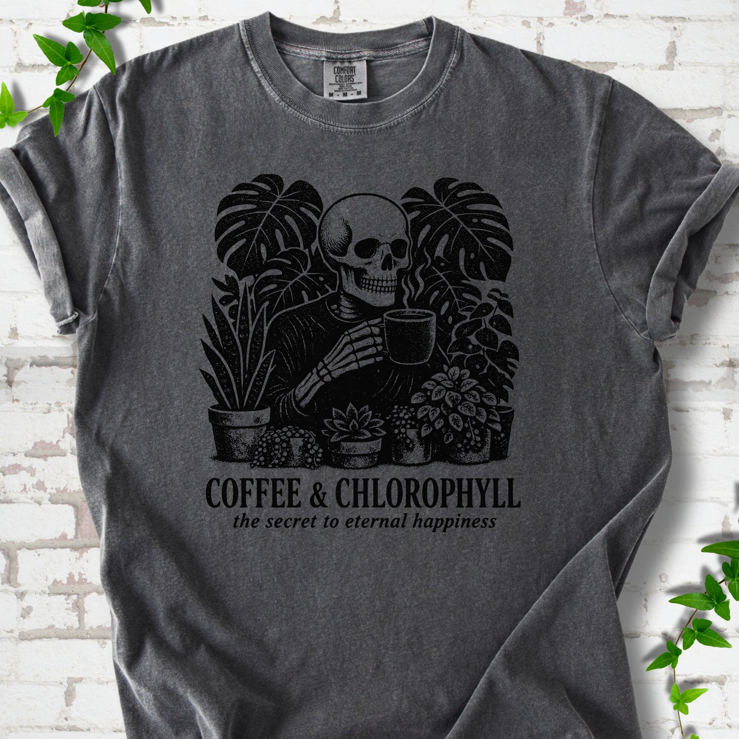 Pepper Comfort Colors® short sleeve T-shirt flat lay featuring a distressed skeleton drinking coffee among houseplants