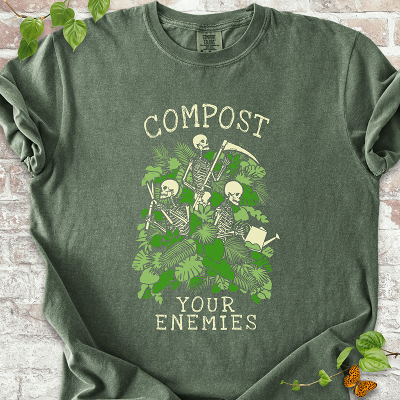 Compost Your Enemies Skeleton T-Shirt on Comfort Colors™ Hemp – shows three skeletons tending to plants with a scythe, trowel, and watering can among vibrant jungle greenery