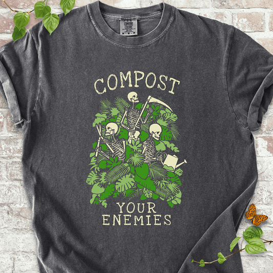 Compost Your Enemies Skeleton T-Shirt on Comfort Colors™ Pepper – features a bold graphic of skeleton gardeners tucked into wild green leaves and layered plant textures