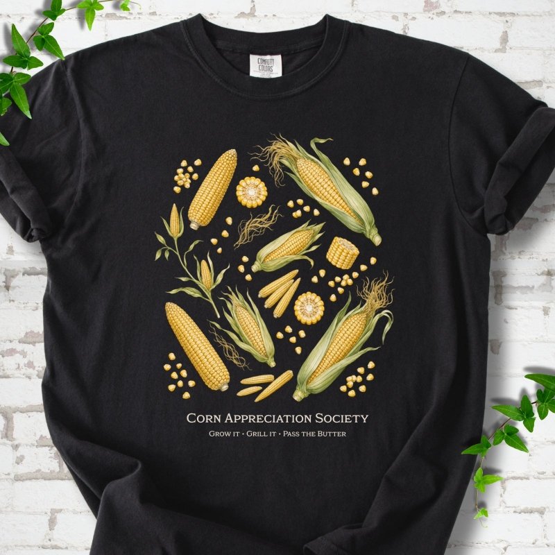 Black Comfort Colors® short sleeve T-shirt flat lay featuring ears, kernels and corn plants with text "Corn Appreciation Society" and "Grow it, grill it, pass the butter"