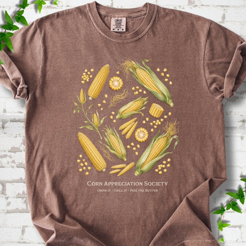 Espresso Comfort Colors® short sleeve T-shirt flat lay featuring ears, kernels and corn plants with text "Corn Appreciation Society" and "Grow it, grill it, pass the butter"
