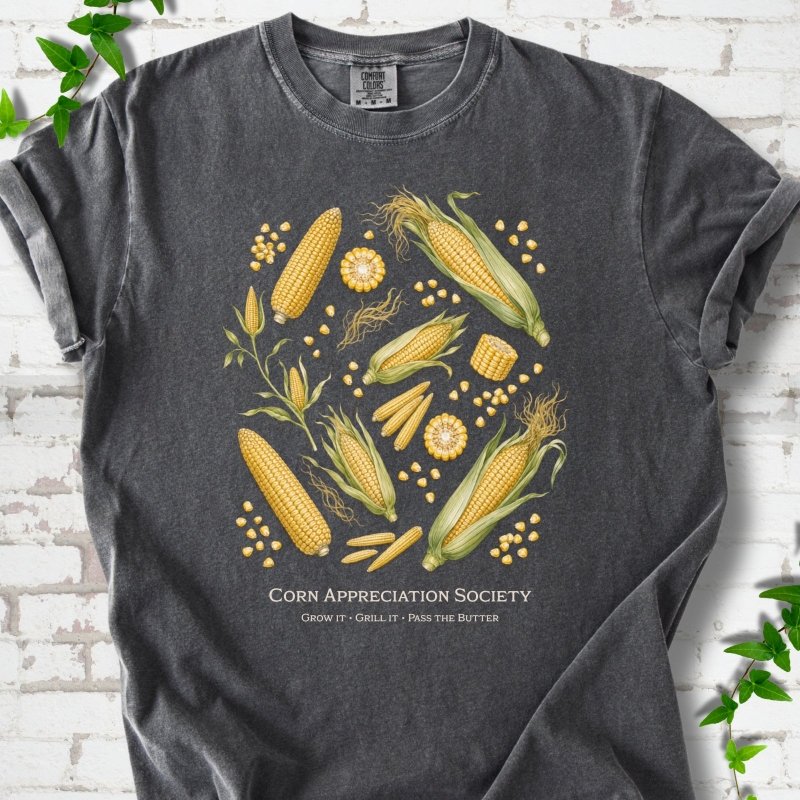 Pepper Comfort Colors® short sleeve T-shirt flat lay featuring ears, kernels and corn plants with text "Corn Appreciation Society" and "Grow it, grill it, pass the butter"