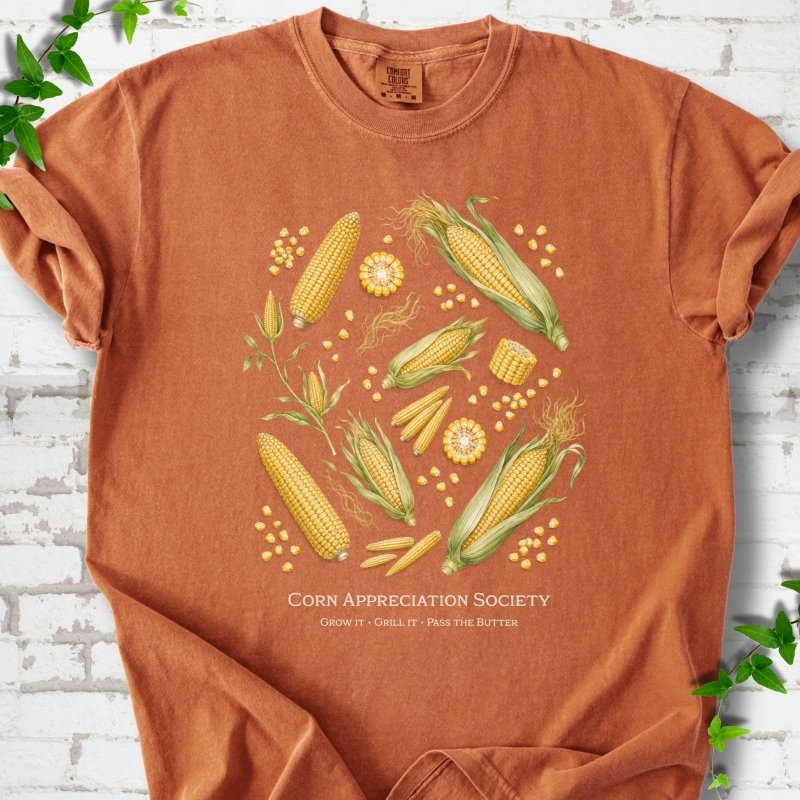 Yam Comfort Colors® short sleeve T-shirt flat lay featuring ears, kernels and corn plants with text "Corn Appreciation Society" and "Grow it, grill it, pass the butter"