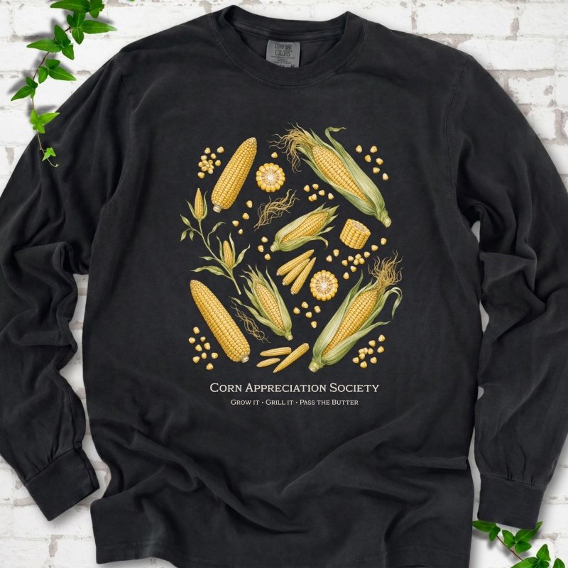 Black Comfort Colors® long sleeve T-shirt flat lay featuring ears, kernels and corn plants with text "Corn Appreciation Society" and "Grow it, grill it, pass the butter"