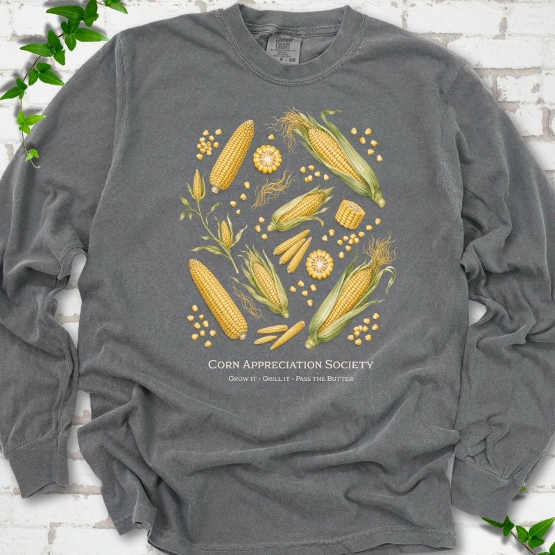 Pepper Comfort Colors® long sleeve T-shirt flat lay featuring ears, kernels and corn plants with text "Corn Appreciation Society" and "Grow it, grill it, pass the butter"