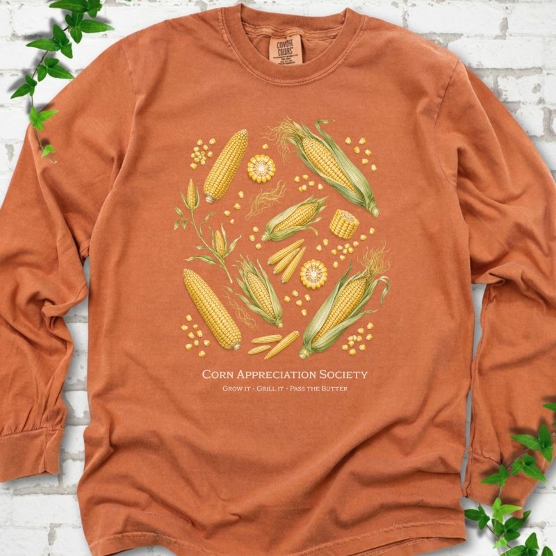 Yam Comfort Colors® long sleeve T-shirt flat lay featuring ears, kernels and corn plants with text "Corn Appreciation Society" and "Grow it, grill it, pass the butter"