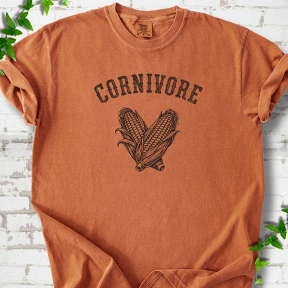 Yam Comfort Colors® short sleeve T-shirt flat lay featuring black line art of two sweet corn cobs beneath the word "Cornivore"