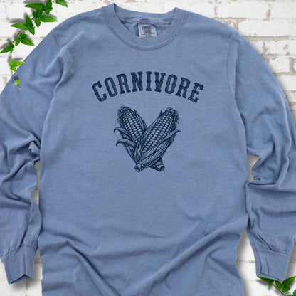 Blue Jean Comfort Colors® long sleeve T-shirt flat lay featuring black line art of two sweet corn cobs beneath the word "Cornivore"