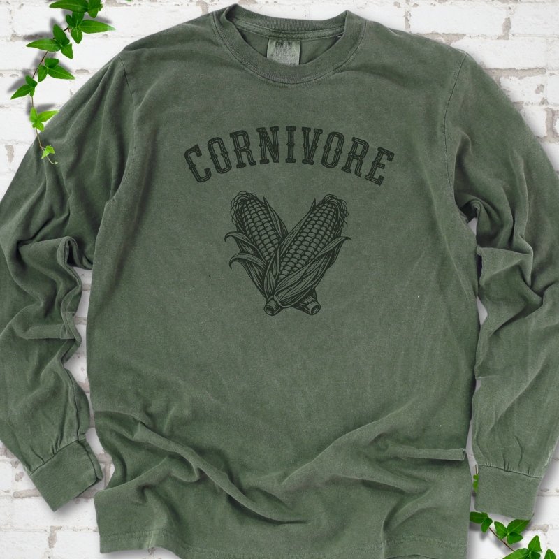 Hemp Comfort Colors® long sleeve T-shirt flat lay featuring black line art of two sweet corn cobs beneath the word "Cornivore"