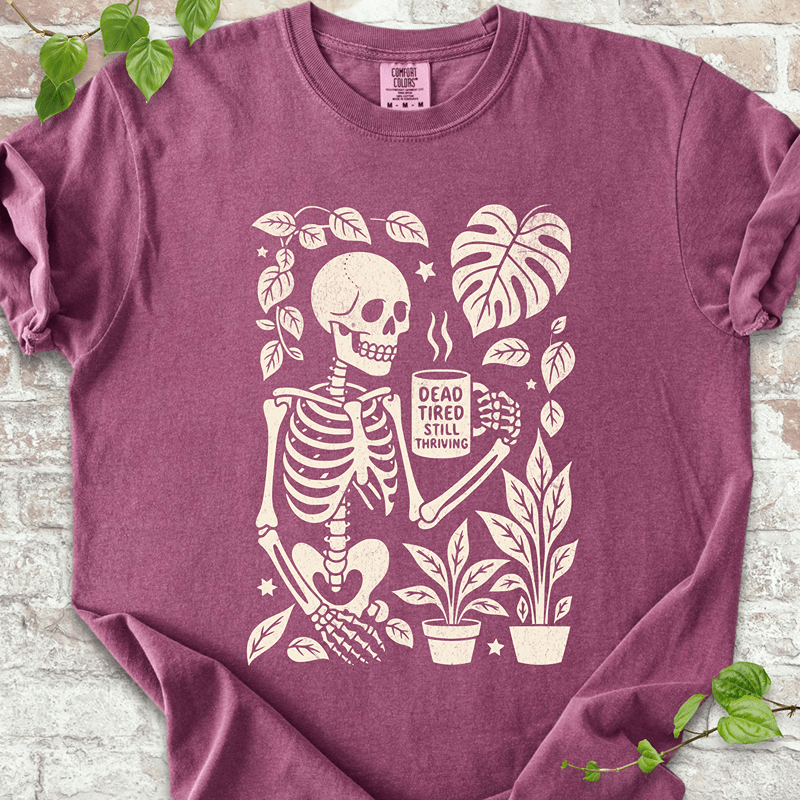 Dead Tired T-shirt on Comfort Colors™ Berry – features a spooky skeleton surrounded by tropical plants, mushrooms, and Monstera leaves in a fall-themed cozy goth style
