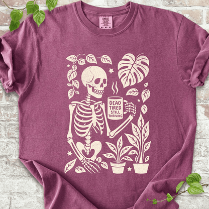 Dead Tired T-shirt on Comfort Colors™ Berry – features a spooky skeleton surrounded by tropical plants, mushrooms, and Monstera leaves in a fall-themed cozy goth style
