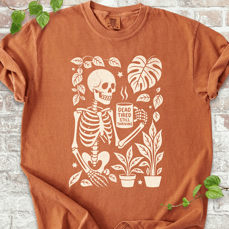 Dead Tired T-shirt on Comfort Colors™ Yam – features a gothic plant-lover skeleton with coffee and foliage accents in warm fall tones