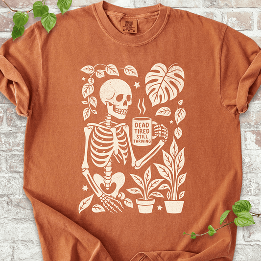 Dead Tired T-shirt on Comfort Colors™ Yam – features a gothic plant-lover skeleton with coffee and foliage accents in warm fall tones