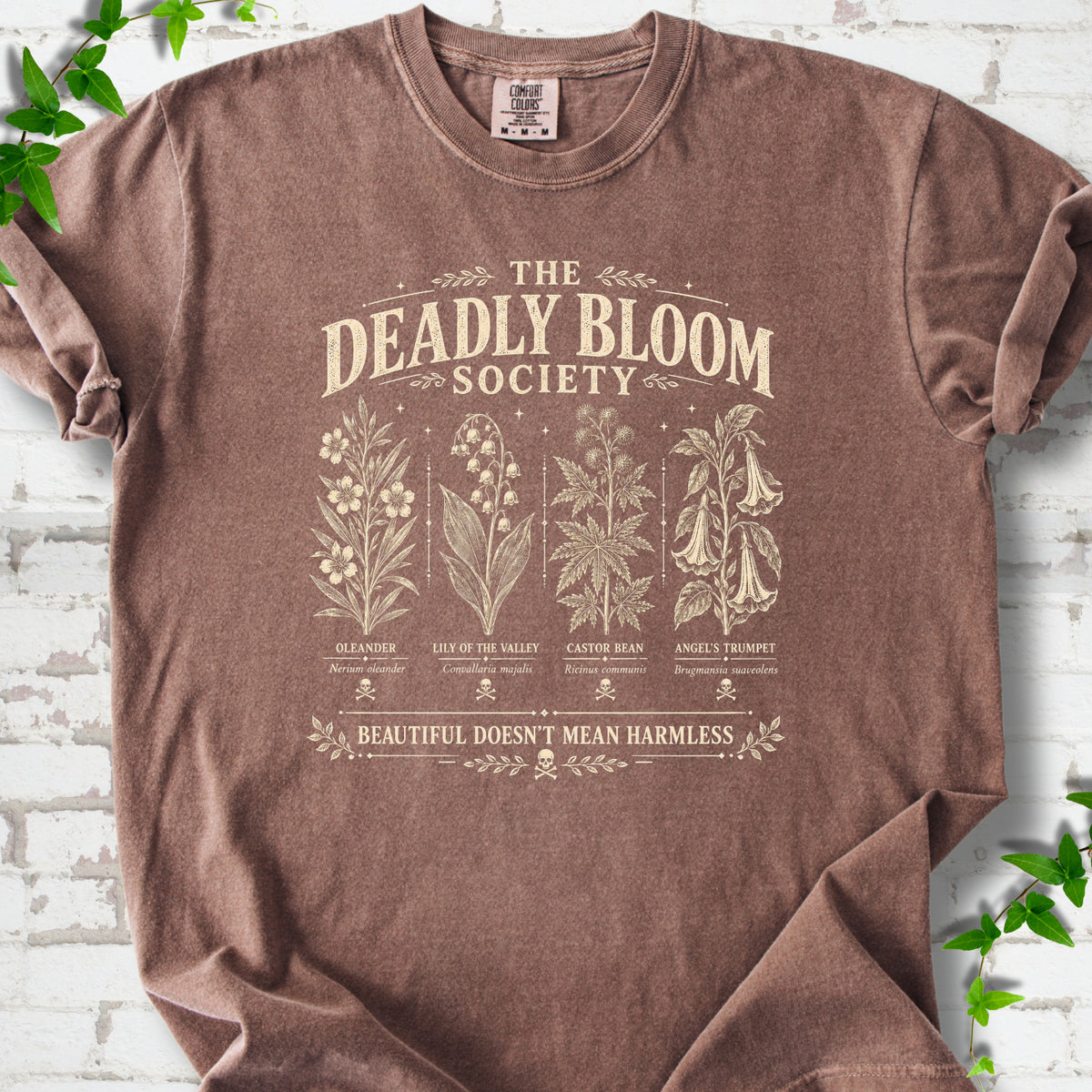 Espresso Comfort Colors® T-shirt flat lay featuring The Deadly Bloom Society poisonous plant design.
