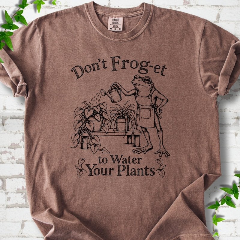 Espresso Comfort Colors® T-shirt laid flat, showing a frog in an apron watering potted plants, with “Don’t Frog-et to Water Your Plants” lettering.