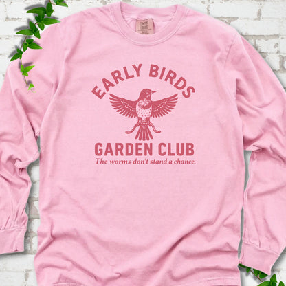 Blossom long sleeve T-shirt laid flat on white brick with greenery. Red bird holding worms between "Early Birds" and "Garden Club" chest lettering.