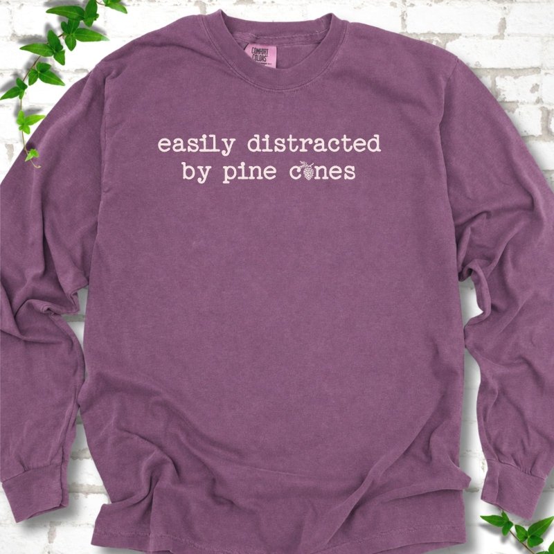 Berry Comfort Colors® long sleeve T-shirt shown flat with "Easily Distracted by Pine Cones" text and a small pine cone graphic