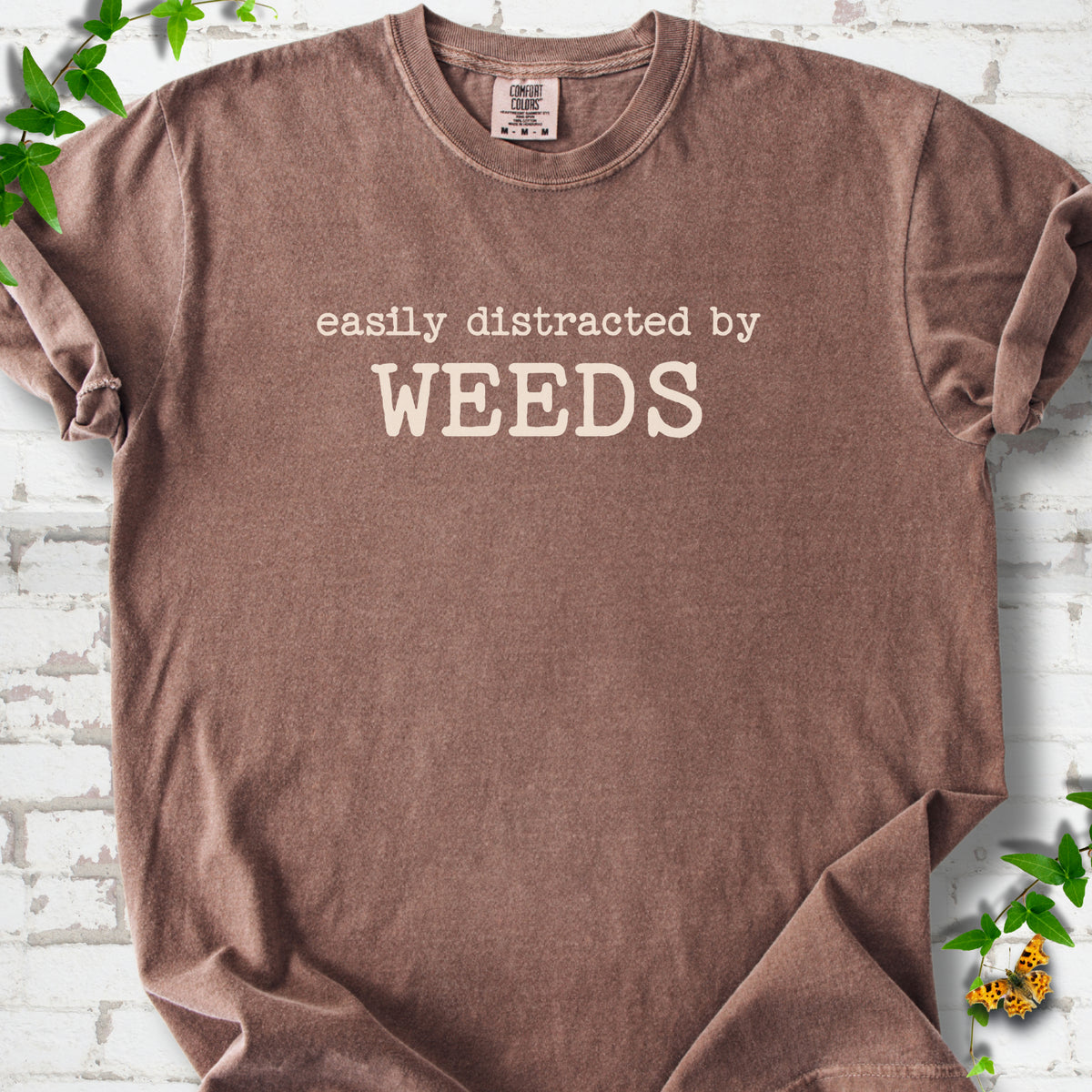 Espresso Comfort Colors® T-shirt shown flat with cream "Easily Distracted by Weeds" gardening slogan