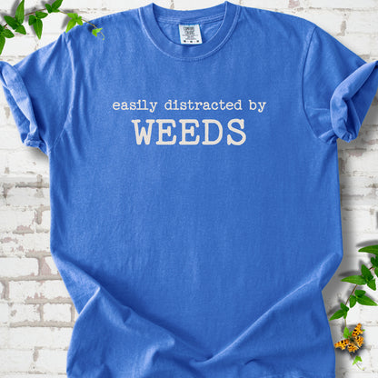 Flo Blue Comfort Colors® T-shirt shown flat with cream "Easily Distracted by Weeds" gardening slogan