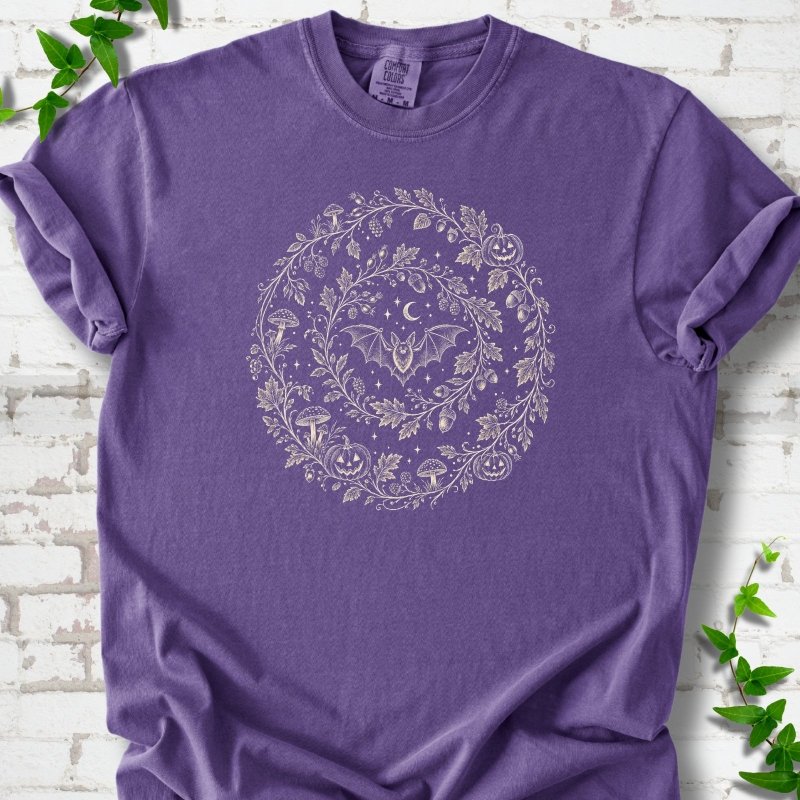 Grape Comfort Colors® T-shirt with cream botanical autumn wreath graphic featuring mushrooms, pumpkins, a bat and crescent moon