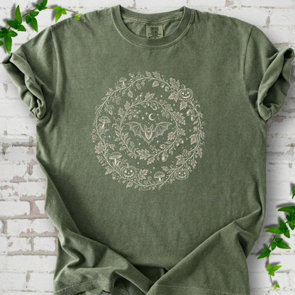 Moss Comfort Colors® T-shirt with cream botanical autumn wreath graphic featuring mushrooms, pumpkins, a bat and crescent moon