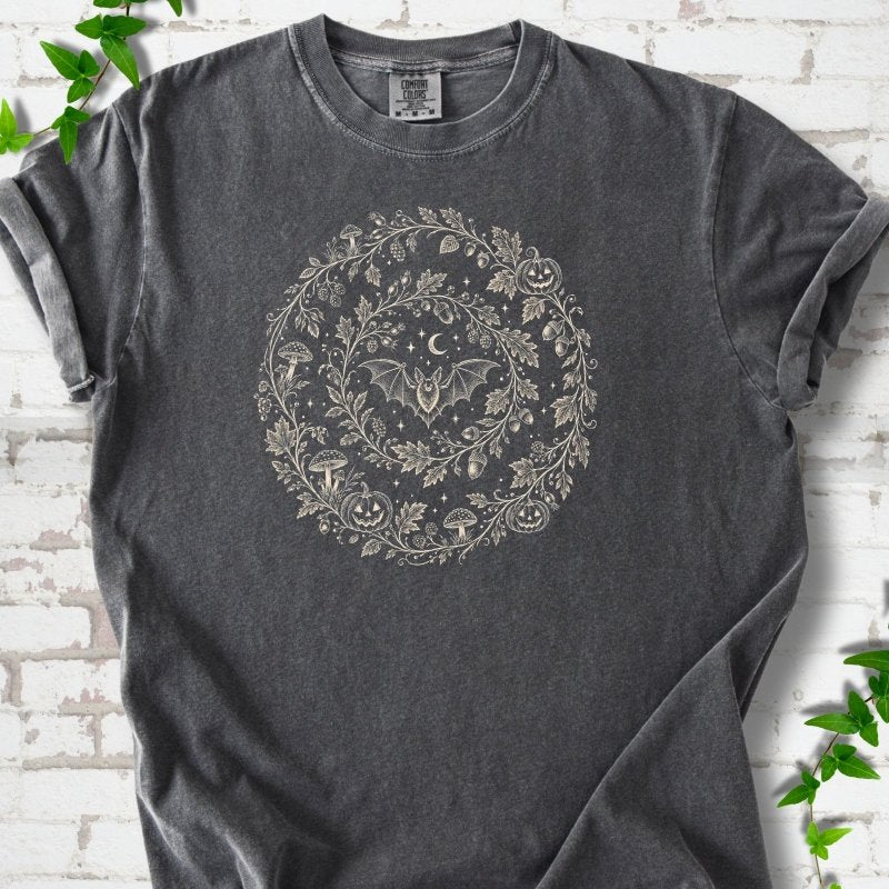Pepper Comfort Colors® T-shirt with cream botanical autumn wreath graphic featuring mushrooms, pumpkins, a bat and crescent moon
