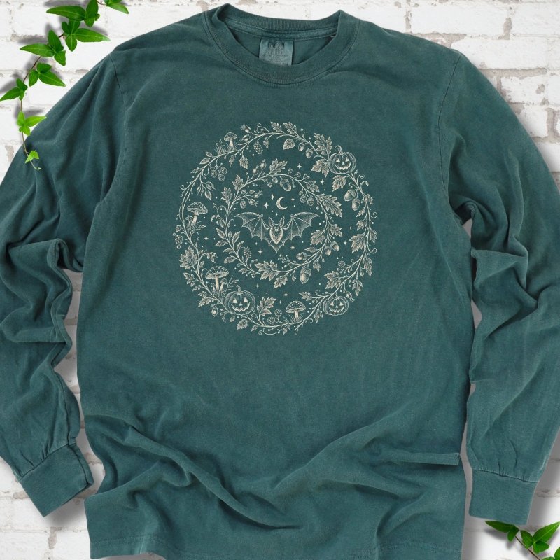 Blue Spruce Comfort Colors® long sleeve T-shirt with cream botanical autumn wreath graphic featuring mushrooms, pumpkins, a bat and crescent moon