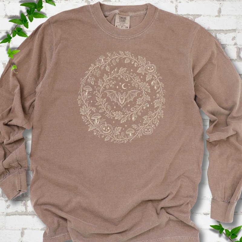 Espresso Comfort Colors® long sleeve T-shirt with cream botanical autumn wreath graphic featuring mushrooms, pumpkins, a bat and crescent moon