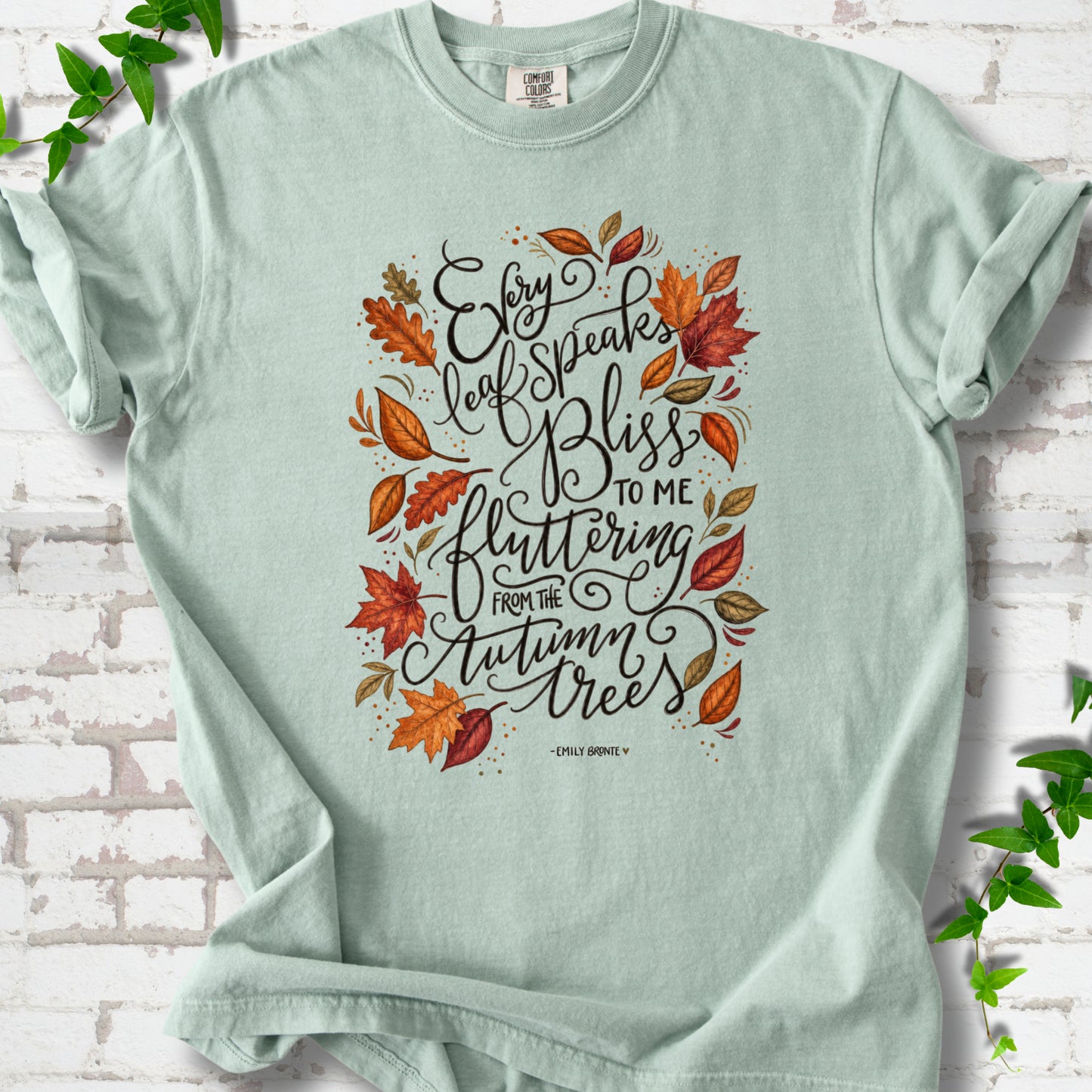 Bay Comfort Colors® T-shirt flat lay with the Every Leaf Speaks Bliss Emily Brontë quote and autumn leaves.
