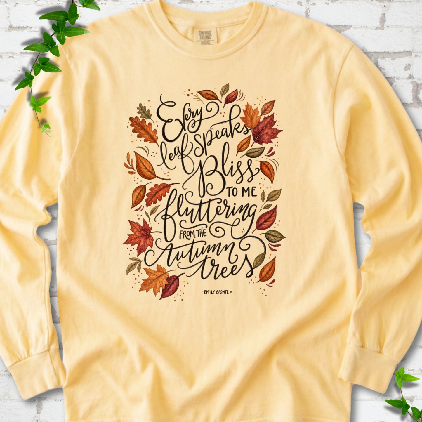 Butter Comfort Colors® long sleeve T-shirt flat lay with the Every Leaf Speaks Bliss Emily Brontë quote and autumn leaves.