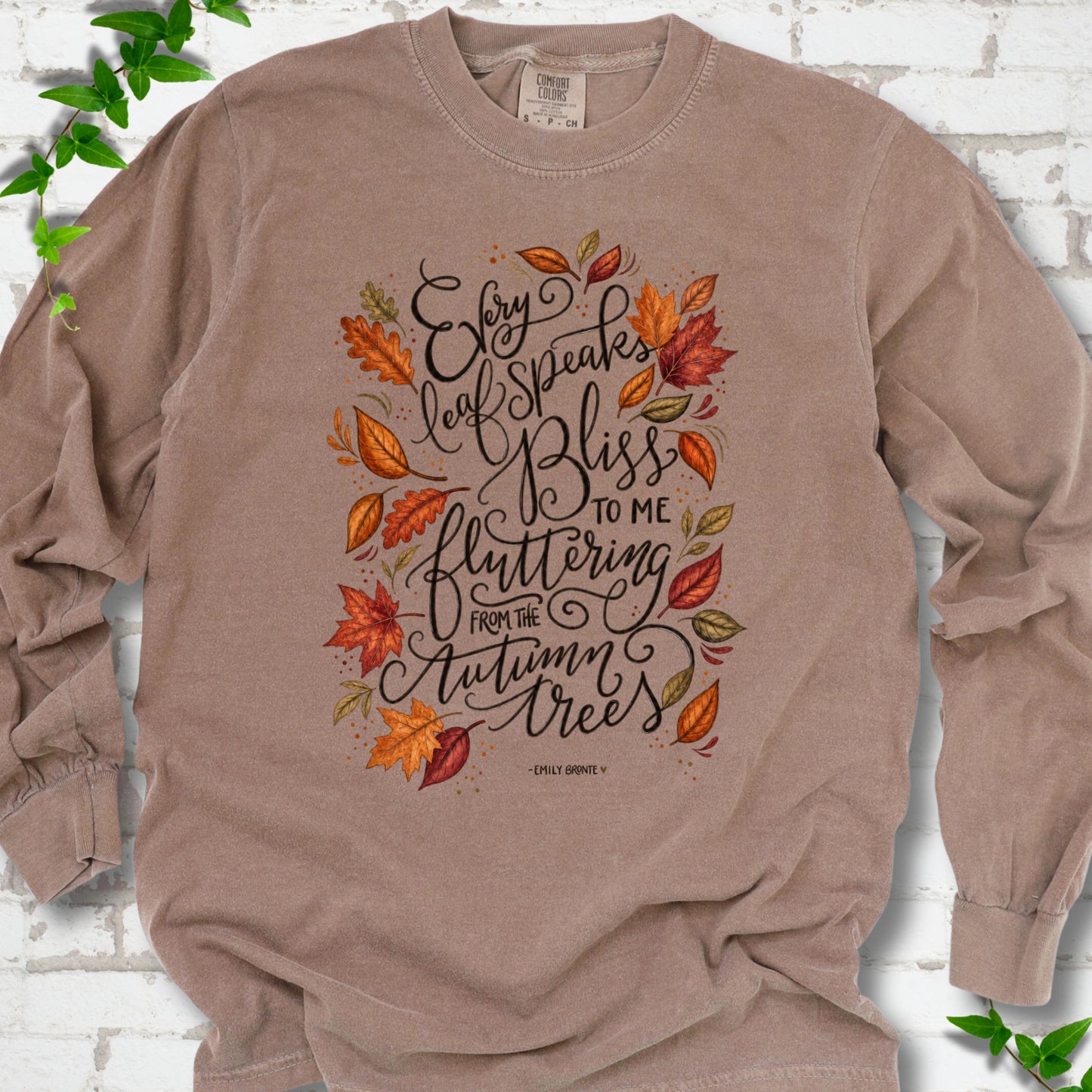 Espresso Comfort Colors® long sleeve T-shirt flat lay with the Every Leaf Speaks Bliss Emily Brontë quote and autumn leaves.