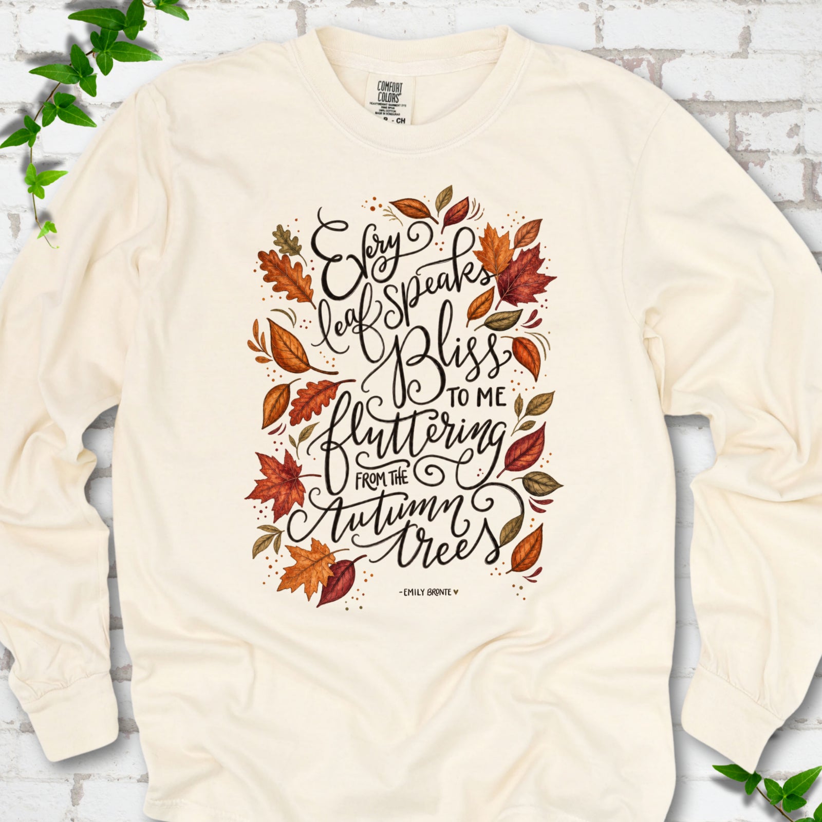 Ivory Comfort Colors® long sleeve T-shirt flat lay with the Every Leaf Speaks Bliss Emily Brontë quote and autumn leaves.