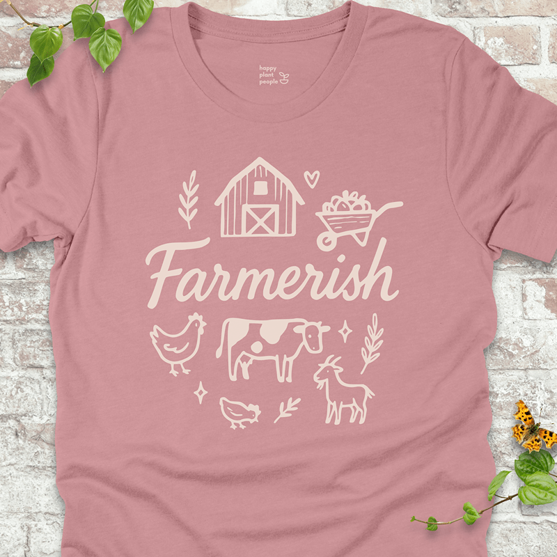 Light pink T-shirt with rustic farmhouse-style graphic and white 'Farmerish' script. Lightweight and soft for everyday wear.