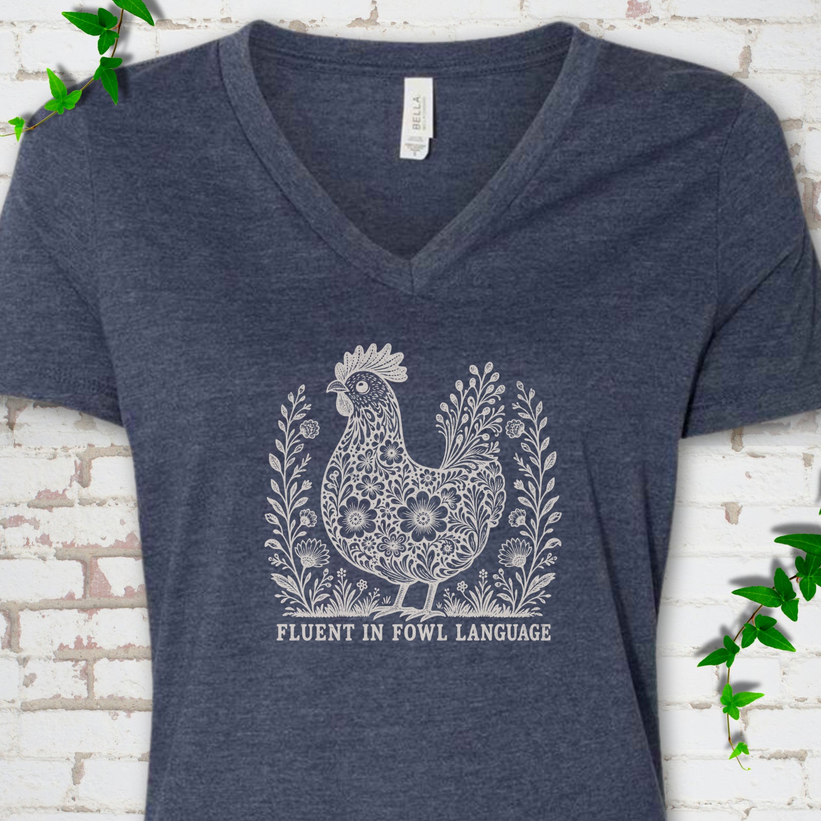 Heather Navy Bella Canvas® V-neck T-shirt with cream floral hen and Fluent in Fowl Language text
