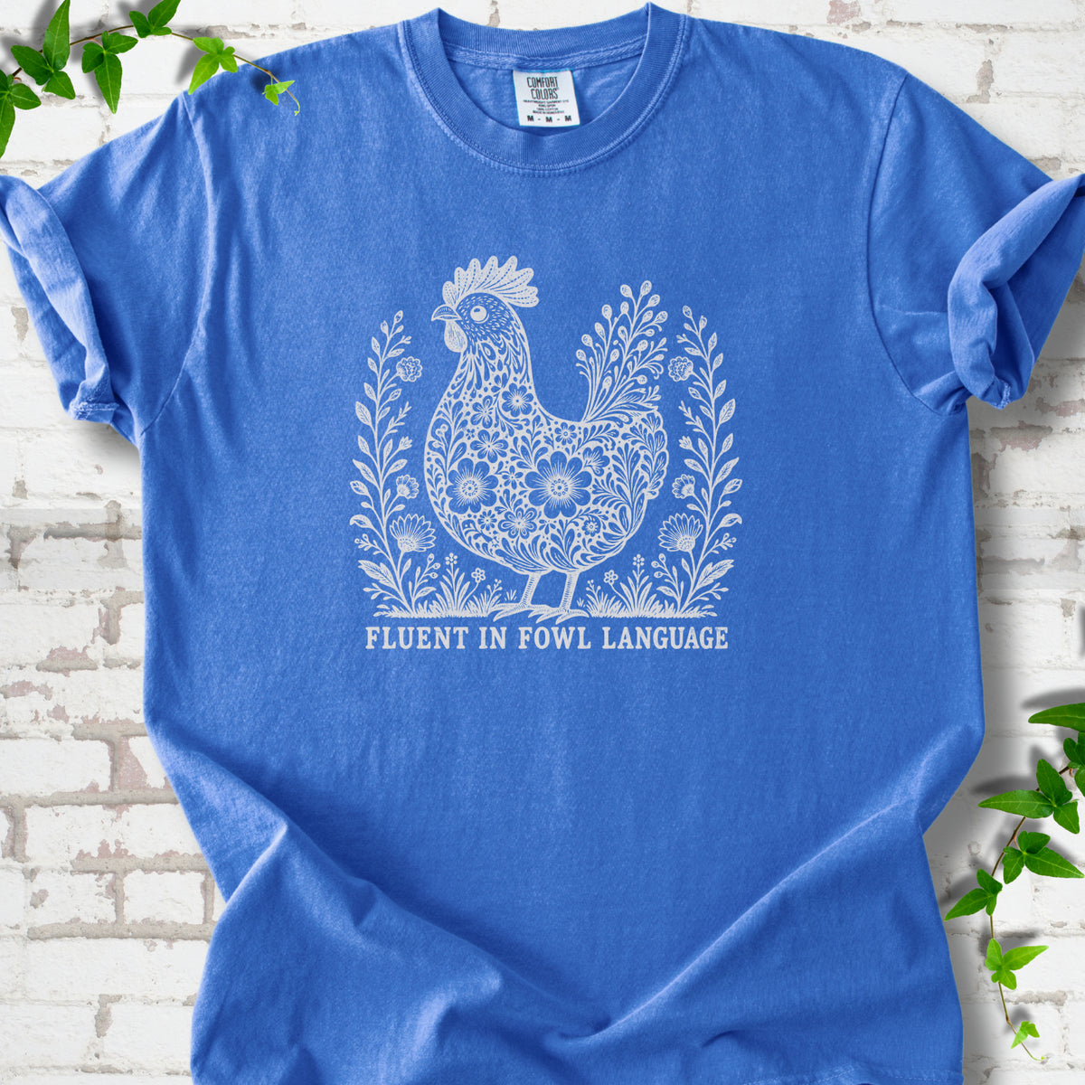 Flo Blue Comfort Colors® T-shirt with cream floral hen and Fluent in Fowl Language text