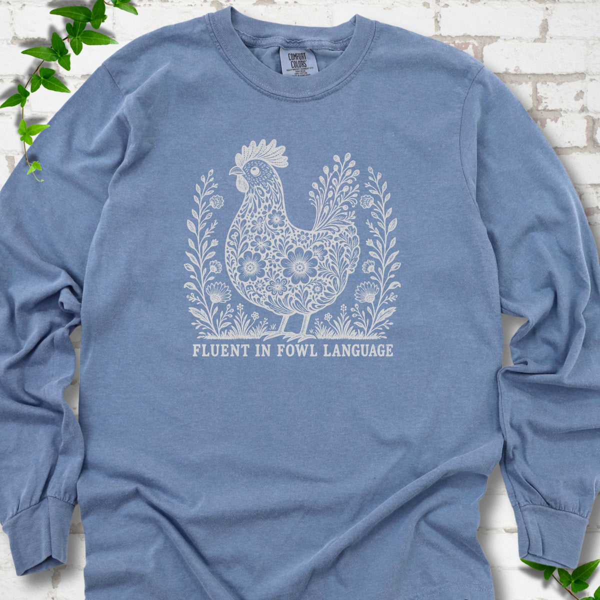 Blue Jean Comfort Colors® long sleeve T-shirt with cream floral hen and Fluent in Fowl Language text